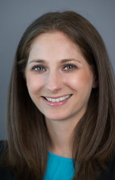 A woman with long brown hair in a blue shirt, smiling gently, showcasing her approachable demeanour.