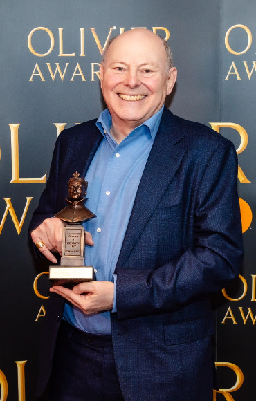 A man celebrating their achievement with trophy in hand at the Olivier Awards